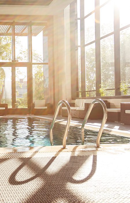 Indoor pool with giants windows and sun shining in.